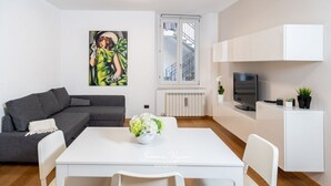 Un soggiorno moderno con un divano grigio, un tavolo da pranzo bianco e un quadro appeso al muro.