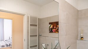 Un bagno con box doccia in vetro, un porta asciugamani e un elemento decorativo a parete.