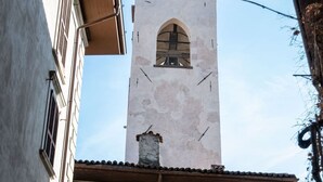 Un'alta torre con una campana, una finestra e un camino.