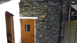 Un muro in pietra con una porta in legno e una piccola finestra.