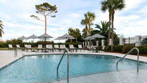 A swimming pool with lounge chairs and umbrellas, surrounded by palm trees and a fence. - Oceanfront Condominium! Beach access, pool, gated. (Saint Simons Island)