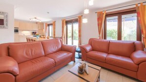A modern living room with two leather sofas, a coffee table, and a kitchen in the background. - Vissershuisje 09/04 with parking by Interhome (Bredene)