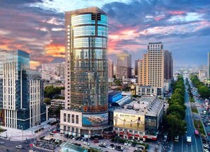 A modern urban cityscape with a prominent curved glass building, a KFC restaurant, and a busy street. - Yun-Zen Century Hotel (Shijiazhuang)