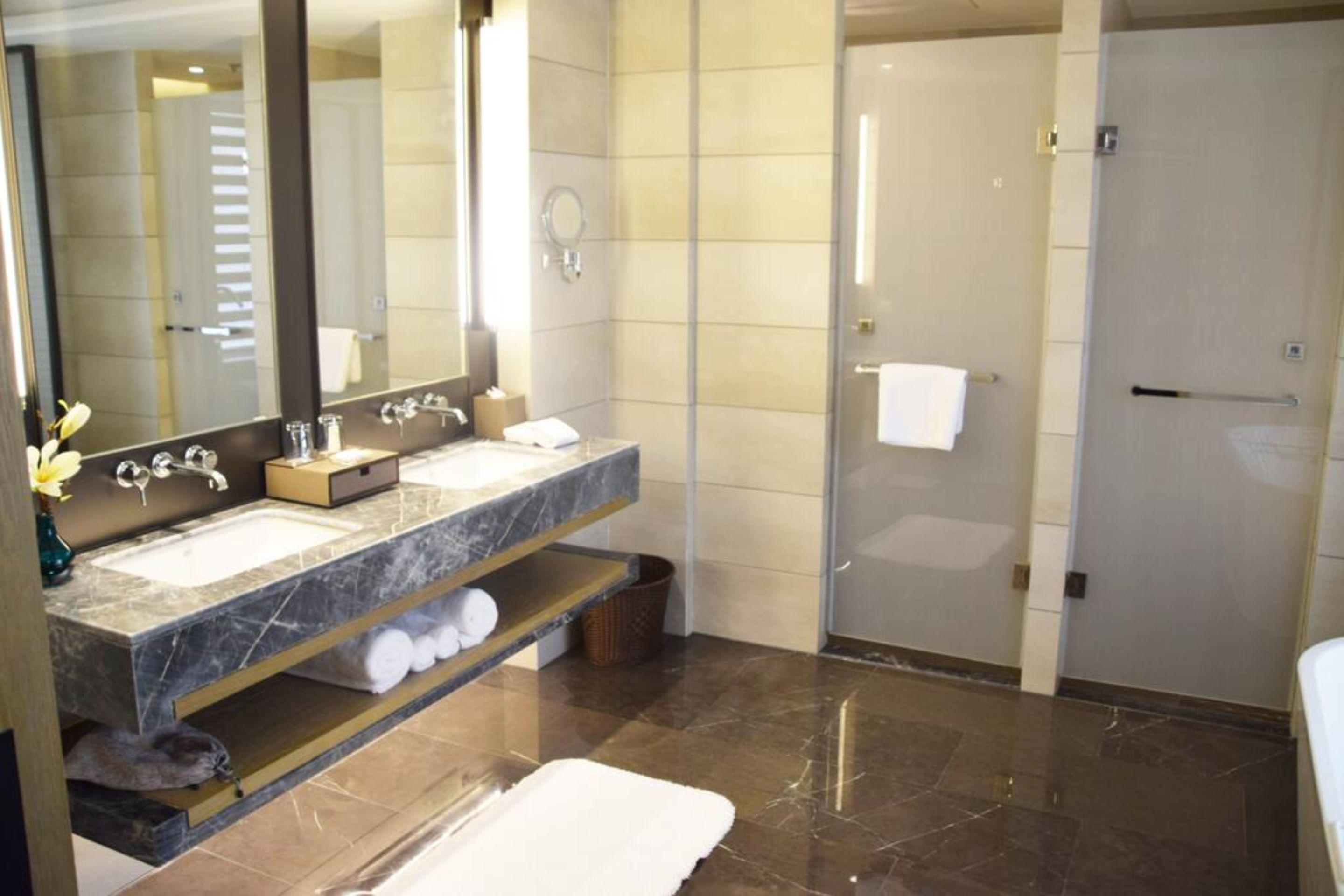 A modern bathroom with two sinks, a large mirror, and a shower area.