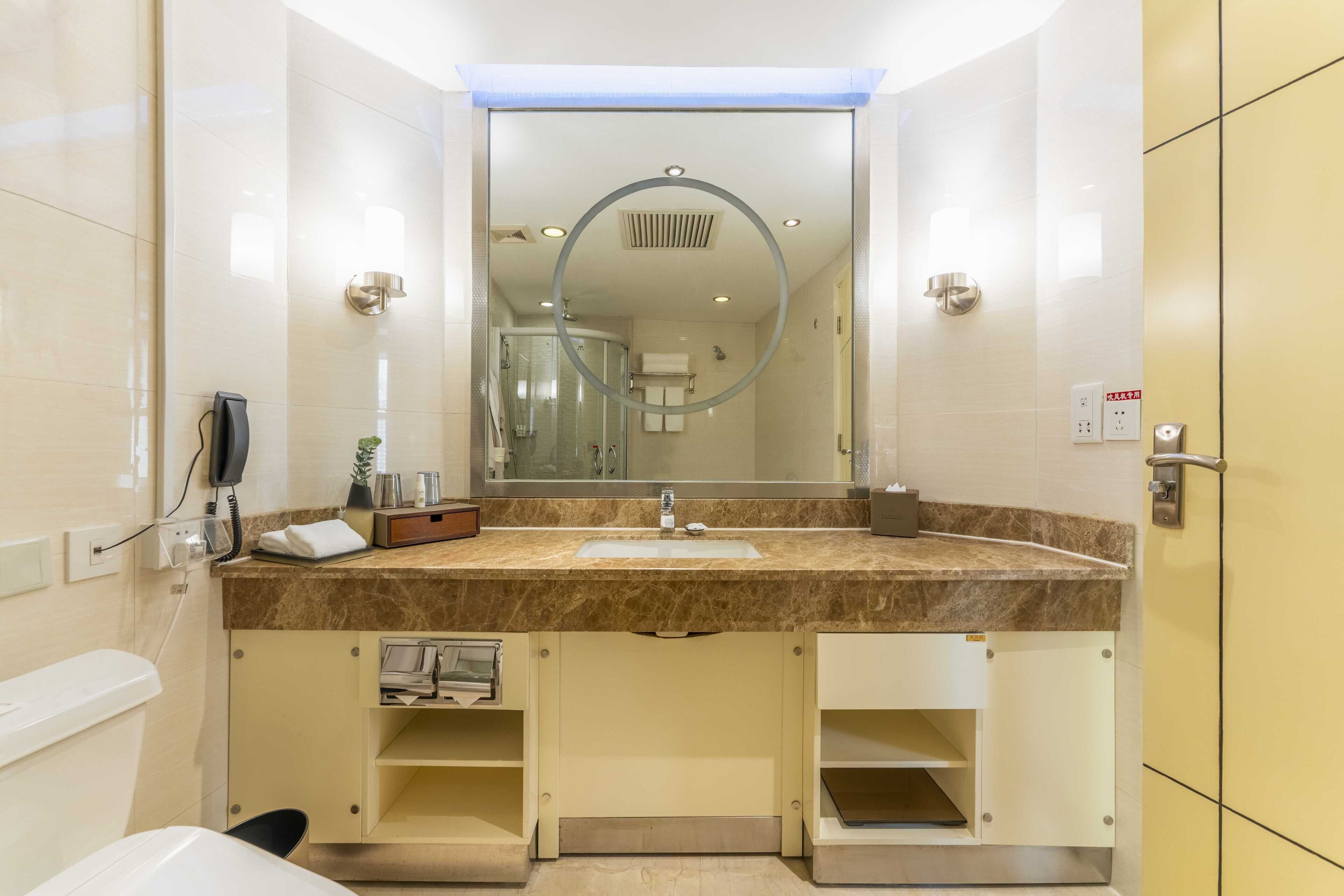 A modern bathroom with a marble sink, a large mirror, and built-in cabinets.