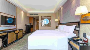 Une chambre d’hôtel avec un grand lit, un bureau avec une lampe, une télévision et un téléphone.