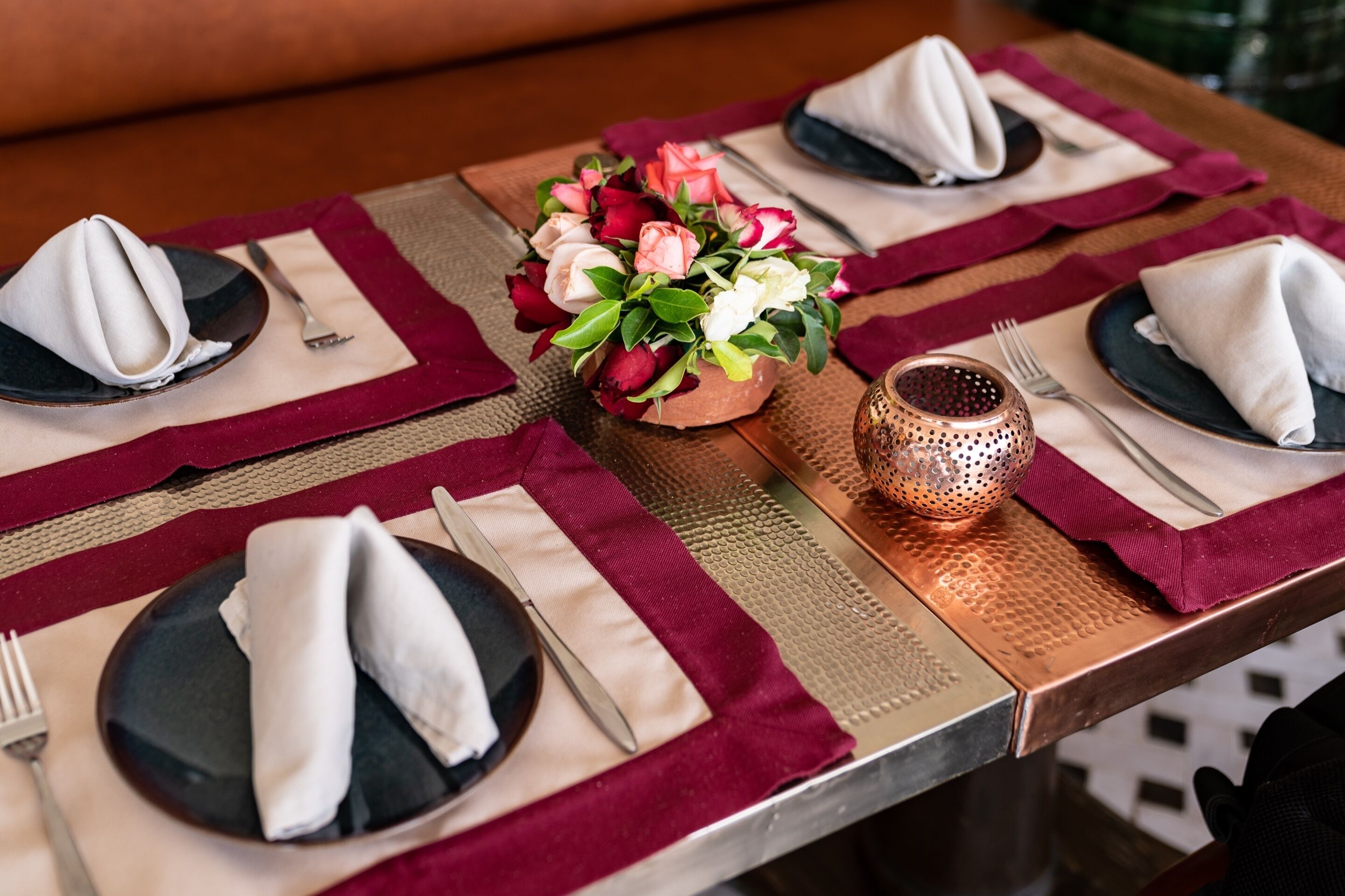 Een tafel gedekt met zwarte borden, witte servetten en een bloemenstuk als decoratie.