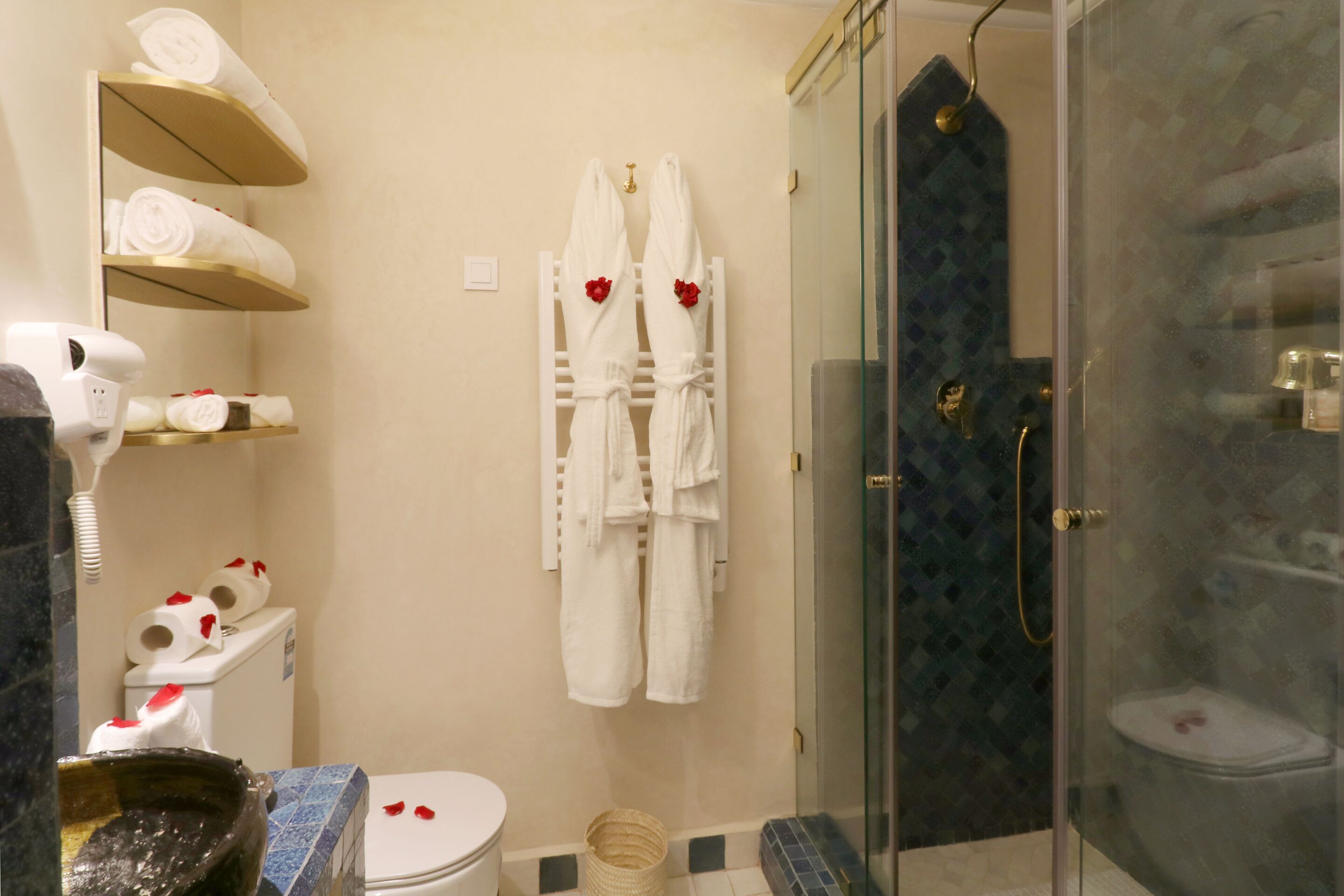 Een badkamer met toilet, een douche met glazen deur en handdoeken op planken.