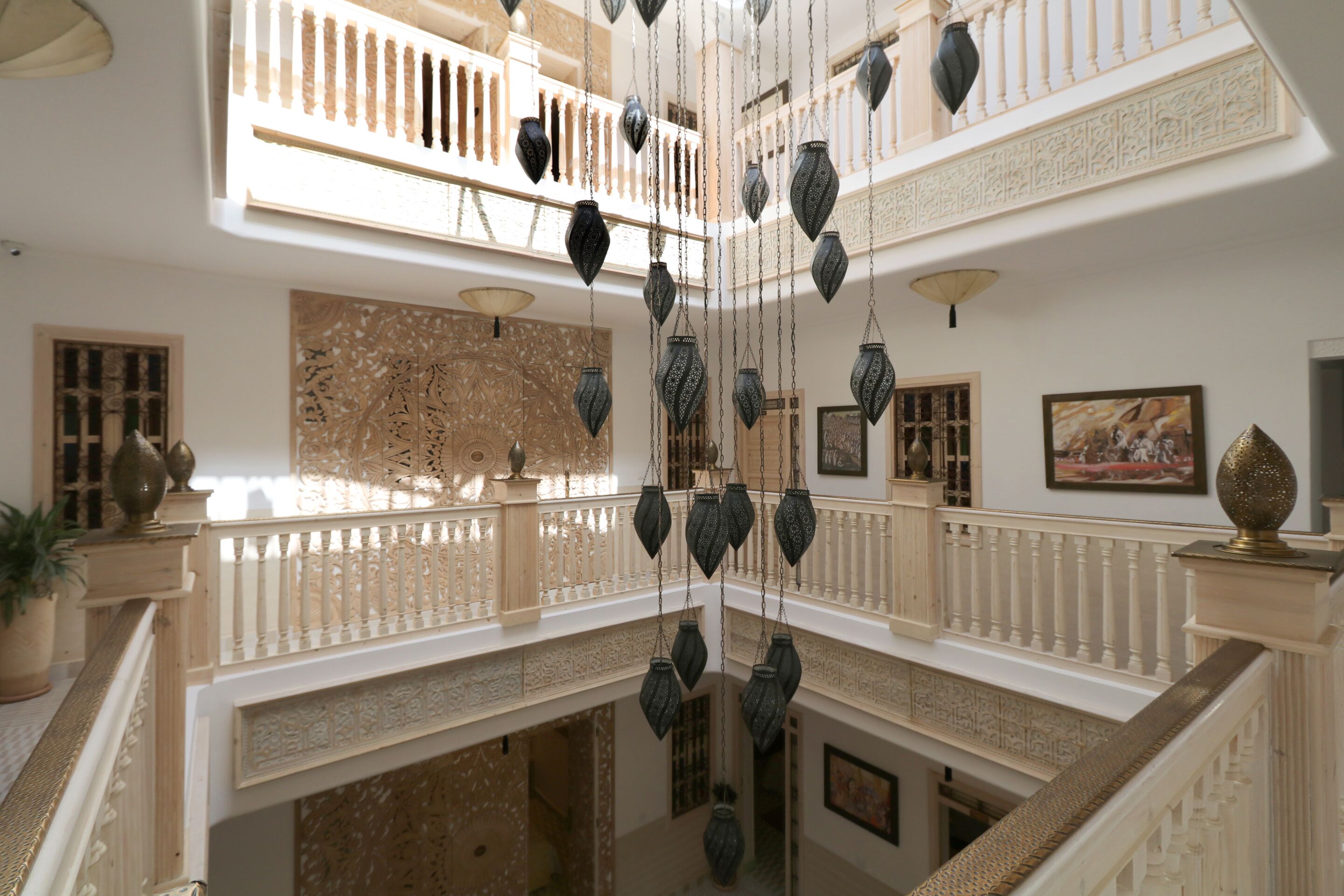 A multi-level interior with ornate railings, hanging lanterns, and decorative wall art.
