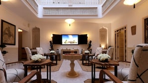 A spacious lounge with a central fountain, seating arrangements, and a television mounted on the wall. - Riad Mareme & Spa (Marrakech)