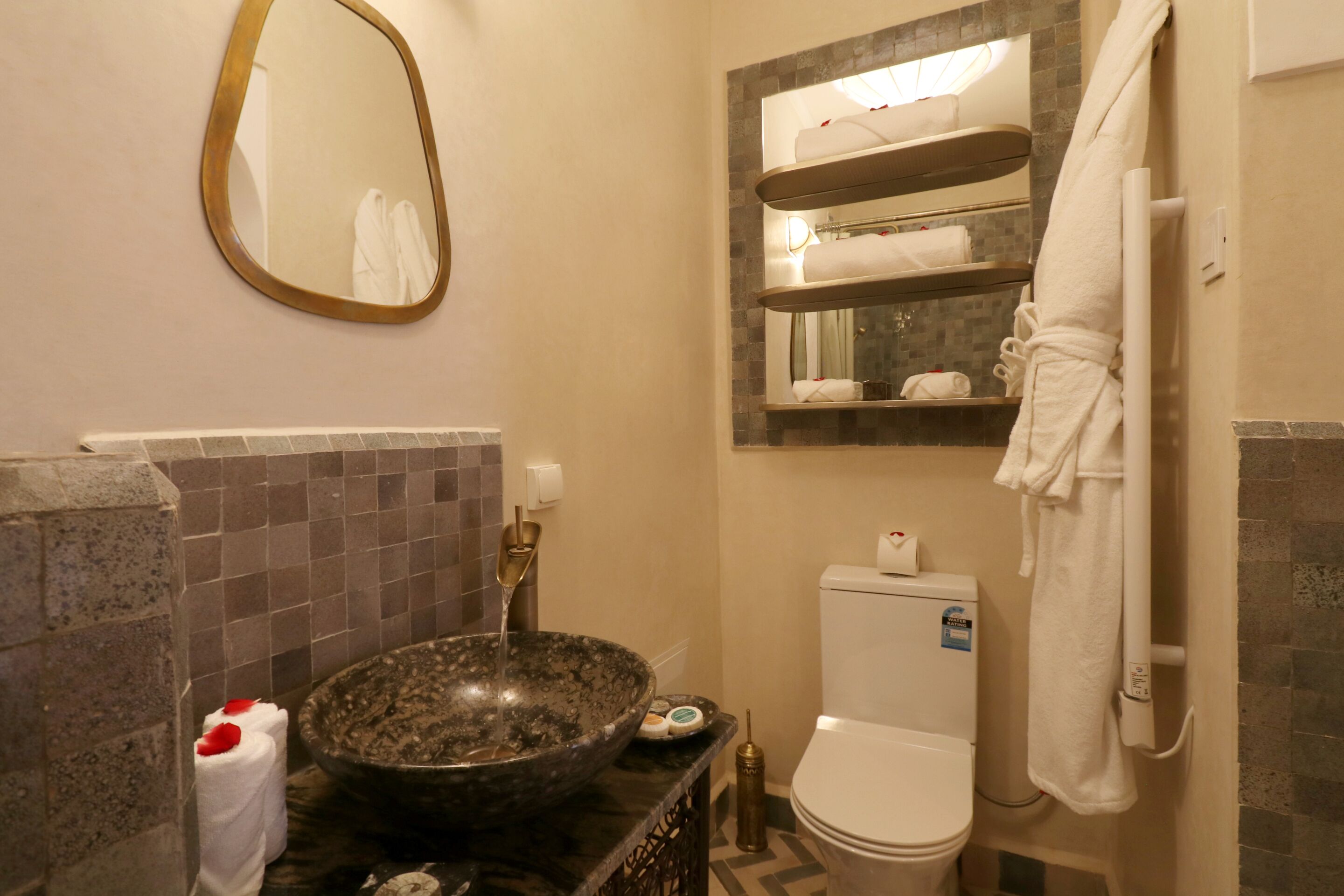 A bathroom with a marble sink, a toilet, a towel rack, and a mirror.
