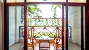 A balcony with wicker furniture and a view of a pool and palm trees. - 36 Manor International Sport Hotel (Vientiane)