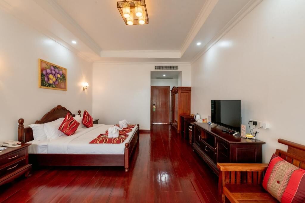 Une chambre d’hôtel avec un lit en bois, une télévision, un bureau et une chaise.