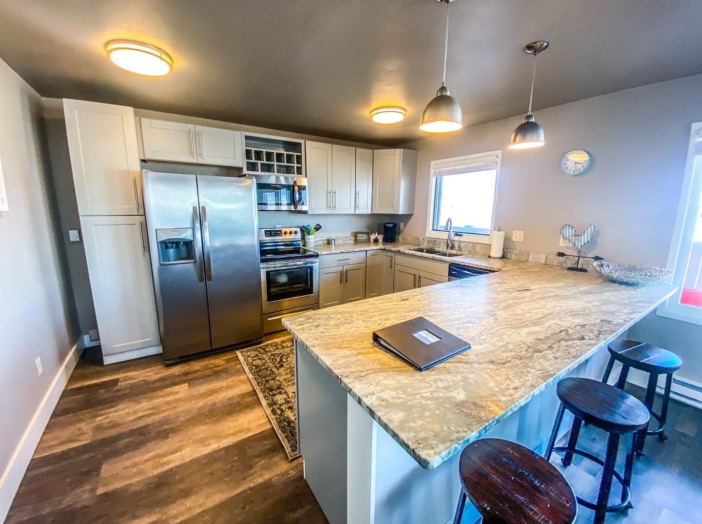 A modern kitchen with stainless steel appliances, a large island, pendant lighting, and a view of the outdoors.
