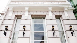 A building facade with a symmetrical window design, decorative moldings, and wall-mounted lanterns. - The Rosewood Torquay (Torquay)