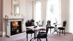 A dining room with a fireplace, ornate chairs, a chandelier, and large windows. - The Rosewood Torquay (Torquay)
