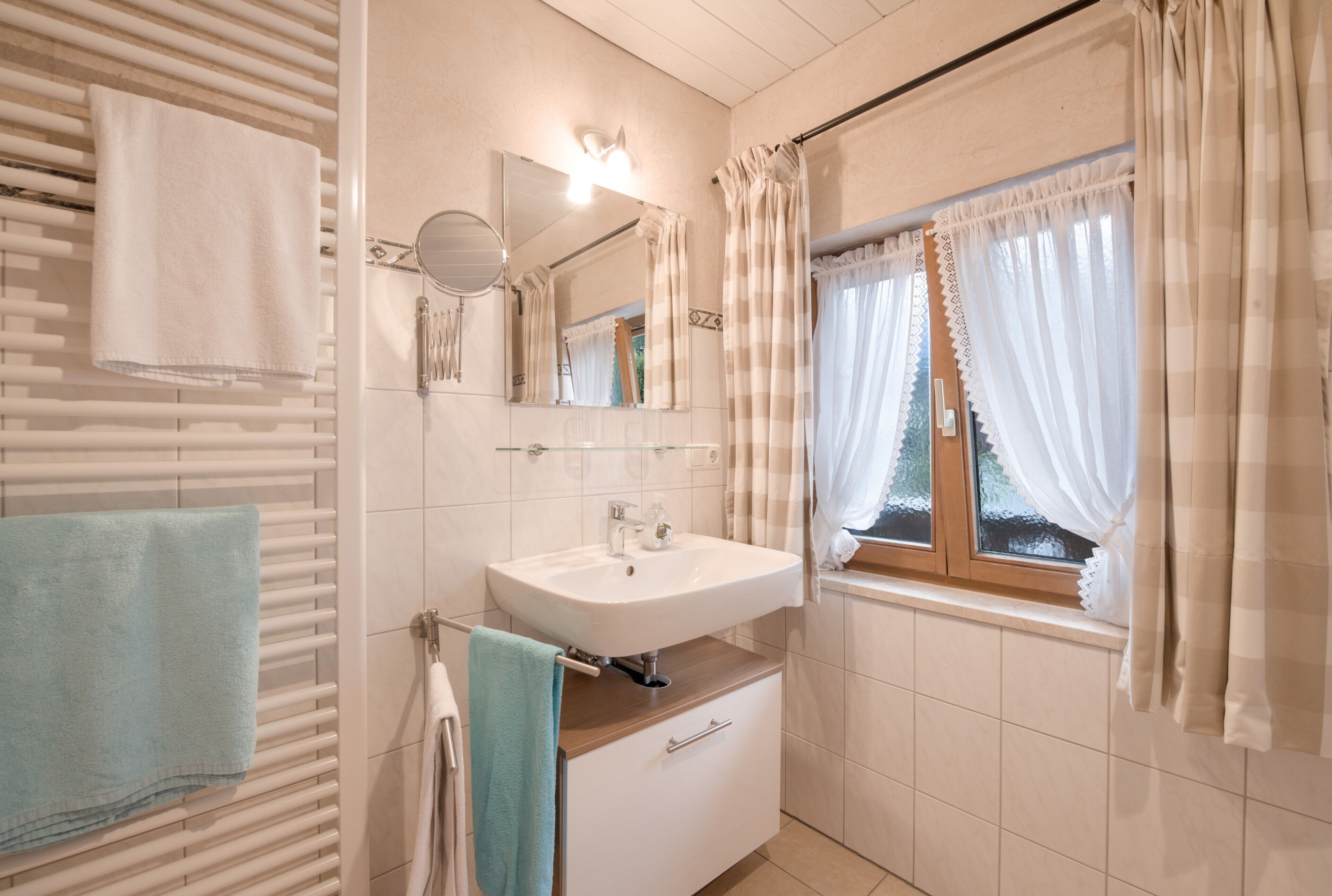 Een badkamer met een witte wasbak, spiegel en handdoekhouder.