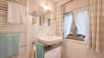 Een badkamer met een witte wasbak, spiegel en handdoekhouder.