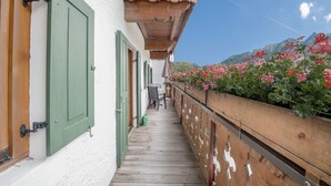 A wooden balcony with a wooden railing, a chair, and a table. - Apartment Waxenstein with Balcony, Mountain View & Wi-Fi (Grainau)