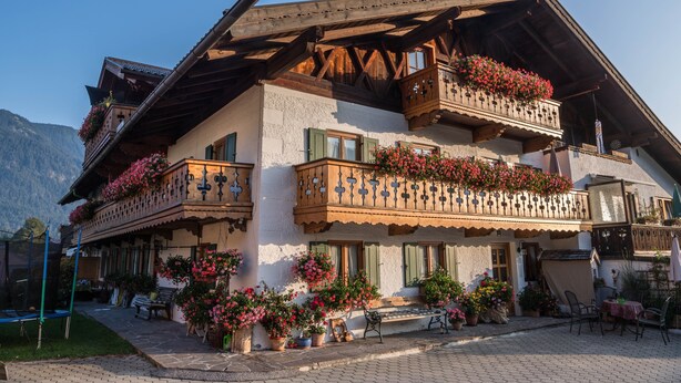A traditional chalet with balconies, potted plants, and outdoor seating. - Apartment Waxenstein with Balcony, Mountain View & Wi-Fi (Grainau)