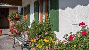 A building with green shutters, a bench, and potted plants with flowers. - Apartment Zugspitze with Terrace, Mountain view & Wi-Fi (Grainau)