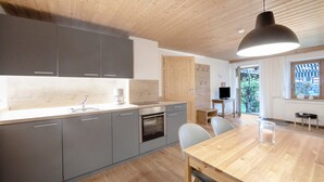 A modern kitchen with grey cabinets, a wooden dining table, and a pendant light. - Apartment Zugspitze with Terrace, Mountain view & Wi-Fi (Grainau)