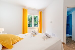 A hotel room with a bed, a window with curtains, a nightstand, and a door leading to a bathroom. - Charming Holiday Home “Vaumera” with Mountain View (SA POBLA)