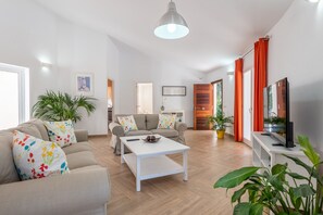 A modern living room with a sofa, coffee table, TV, and potted plants. - Charming Holiday Home “Vaumera” with Mountain View (SA POBLA)