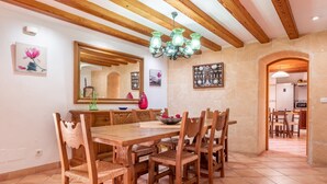Un coin repas avec une table et des chaises en bois, un lustre et un miroir au mur.