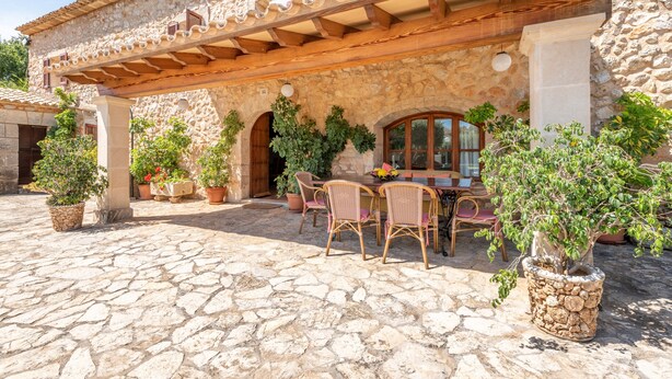 Un bâtiment en pierre doté d’un patio couvert, d’un espace extérieur aménagé pour s’asseoir et de plantes en pot.