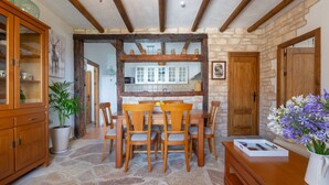 A rustic dining area with stone flooring, wooden furniture, and a stone wall. - Luxury Villa Casa el Impero with Pool, Terrace, Unique Mountain View and WiFi (Gaucin)