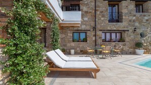 A stone building with a pool, lounge chairs, and a table with chairs. - Luxury Villa Casa el Impero with Pool, Terrace, Unique Mountain View and WiFi (Gaucin)
