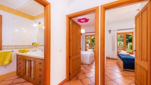 A hotel room with a bathroom, a bed, and a view of the outdoors. - “Ca Na Rosa” close to the Beach with Wi-Fi, A/C, Terrace, Garden & Pool (ALCUDIA)