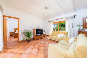 A living room with a sofa, TV, potted plants, and a wooden cabinet.