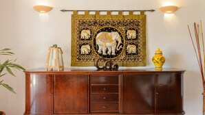 A wooden cabinet with drawers, a decorative tapestry with elephants, a lantern, and a vase. - Holiday Apartment "Can Jordi" with Mountain Views (Sant Josep de sa Talaia)