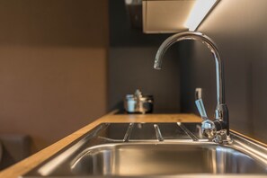 A stainless steel kitchen sink with a modern faucet, a wooden countertop, and a small appliance in the background. - Dolomites View Apartment "Durnbrunn 2" with Mountain View, Wi-Fi, Garden & Terrace (Olang)