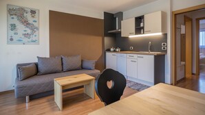 A modern living space with a sofa, a dining table, a kitchen area, and a map on the wall.