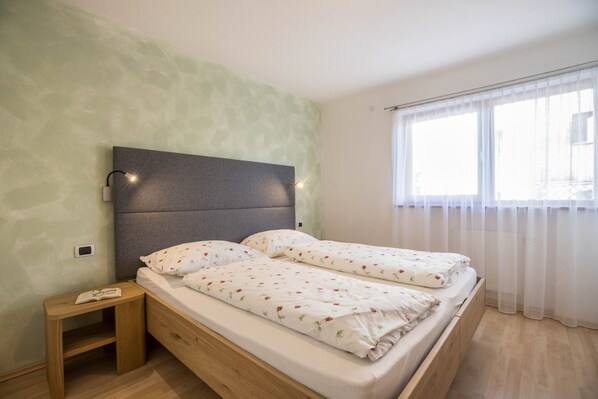 Une chambre à coucher avec un lit, une table de chevet et une fenêtre avec des rideaux.