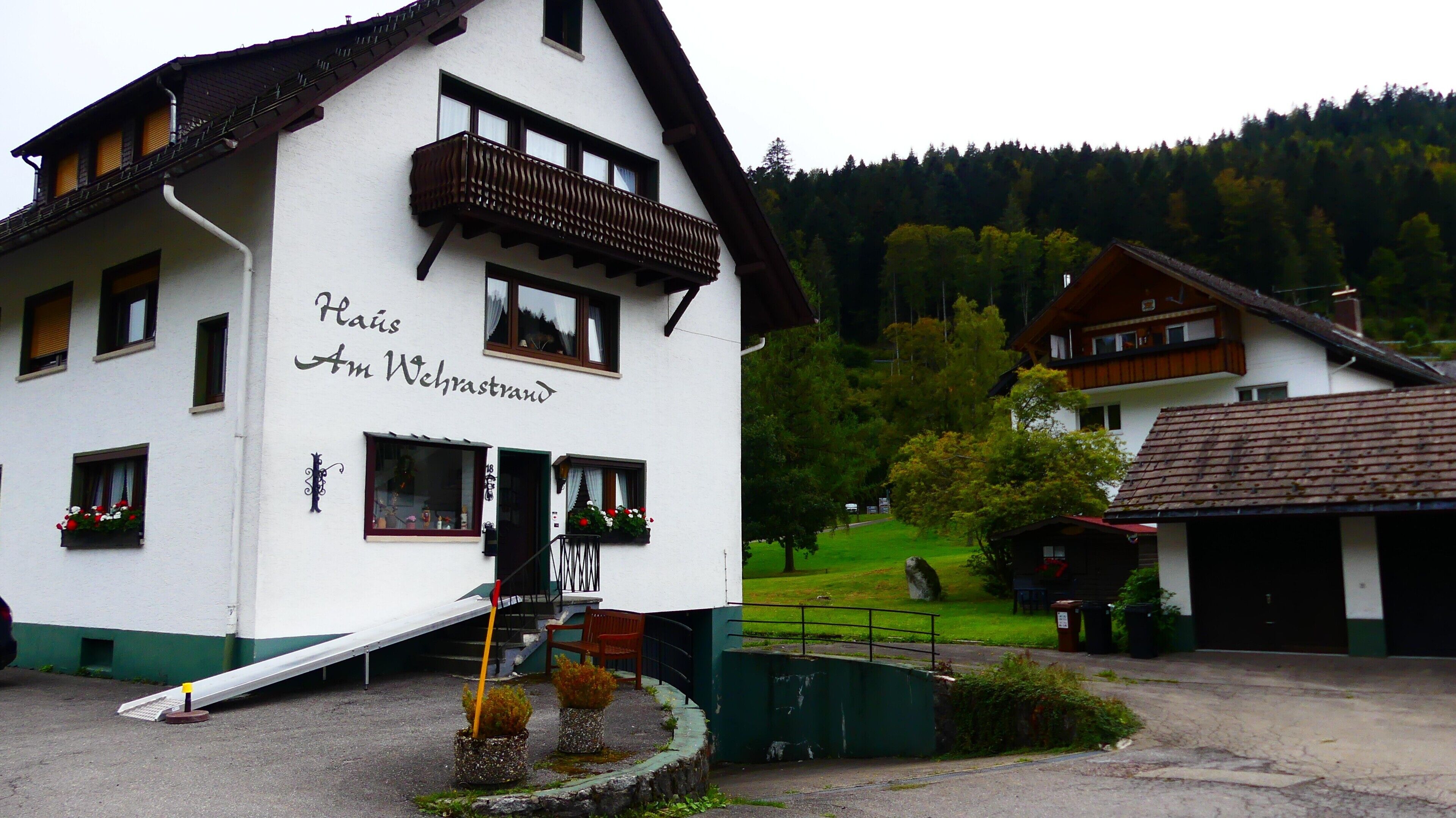 Un bâtiment blanc doté d’un balcon, d’une rampe et d’une enseigne indiquant « Häus Am Wehrstrand ».