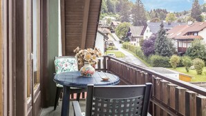 Ein Balkon mit Tisch, Stühlen und einem Blumenstrauß.