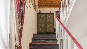 Eine Treppe mit Holzbeschlägen, ein grünes Schrankschrank mit floralen Verzierungen und ein rotes Geländer.