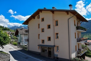 Un edificio a più piani con balconi, un piccolo ingresso e vista sulle montagne.