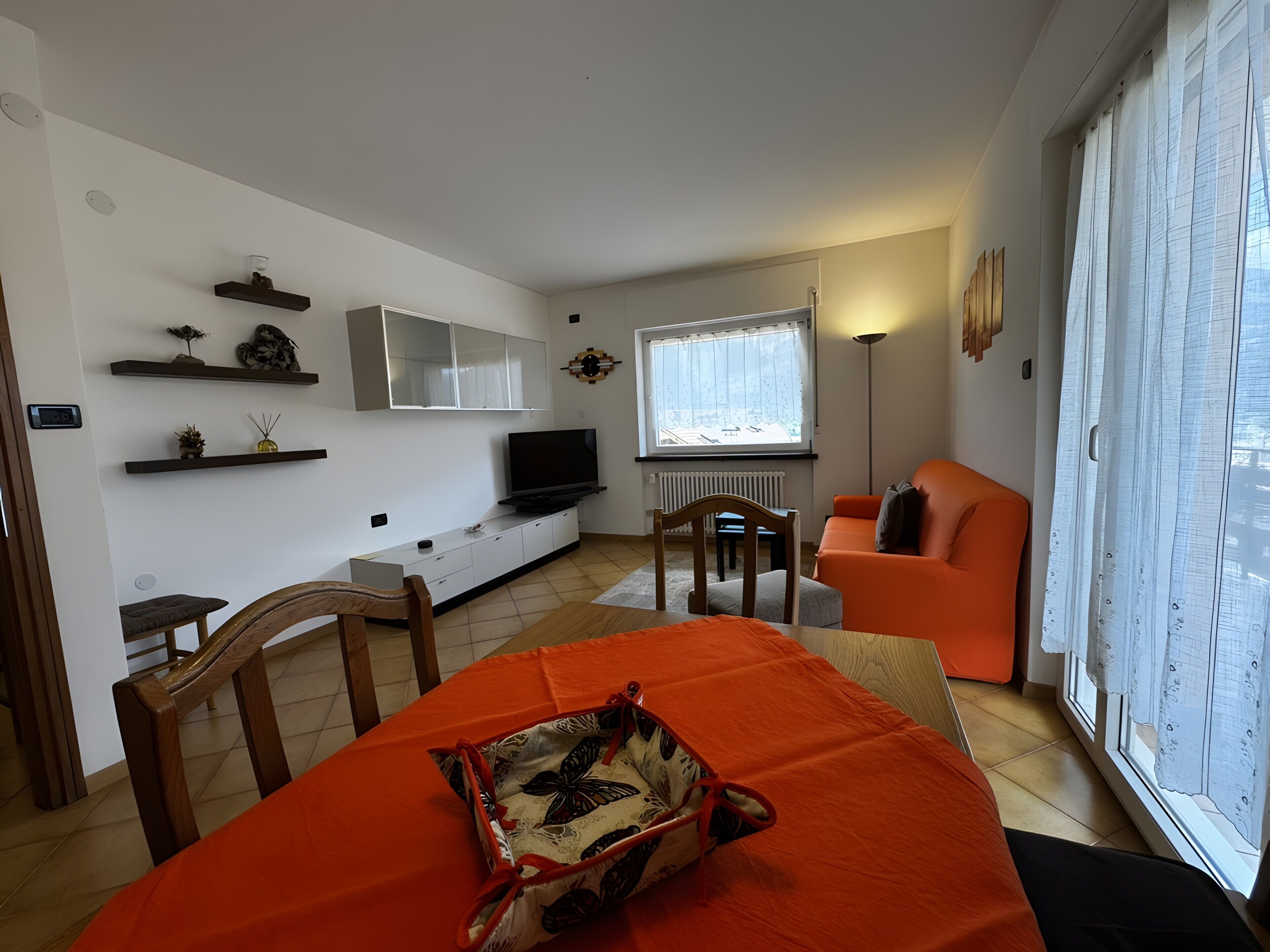 Sala de estar moderna com sofá, televisão e área de jantar com mesa e cadeiras.