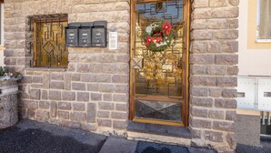 A stone building with a golden door, a mailbox, and a wreath. - Child-friendly Holiday Apartment "Cornon" with Mountain View, Sun Terrace & Wi-Fi (Tesero)