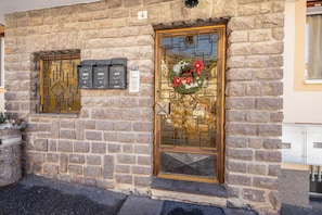 Un edificio de piedra con una puerta dorada, un buzón y una corona decorativa.
