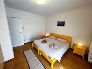 Una camera da letto con un letto, comodini, un tappeto e un quadro appeso al muro.