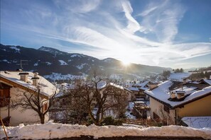 A snow-covered village with houses, a mountain range, and a clear sky.
