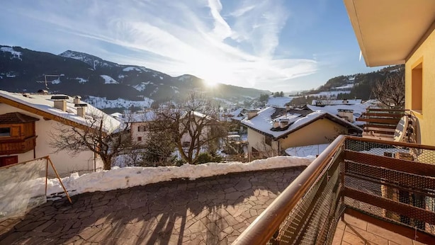 A balcony with a view of a snow-covered village and mountains. - Child-friendly Holiday Apartment "Cornon" with Mountain View, Sun Terrace & Wi-Fi (Tesero)