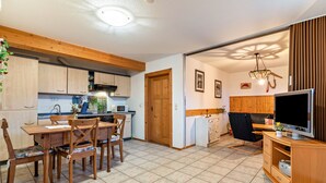 Un espacio habitable compacto con cocina, comedor y televisor en la sala.