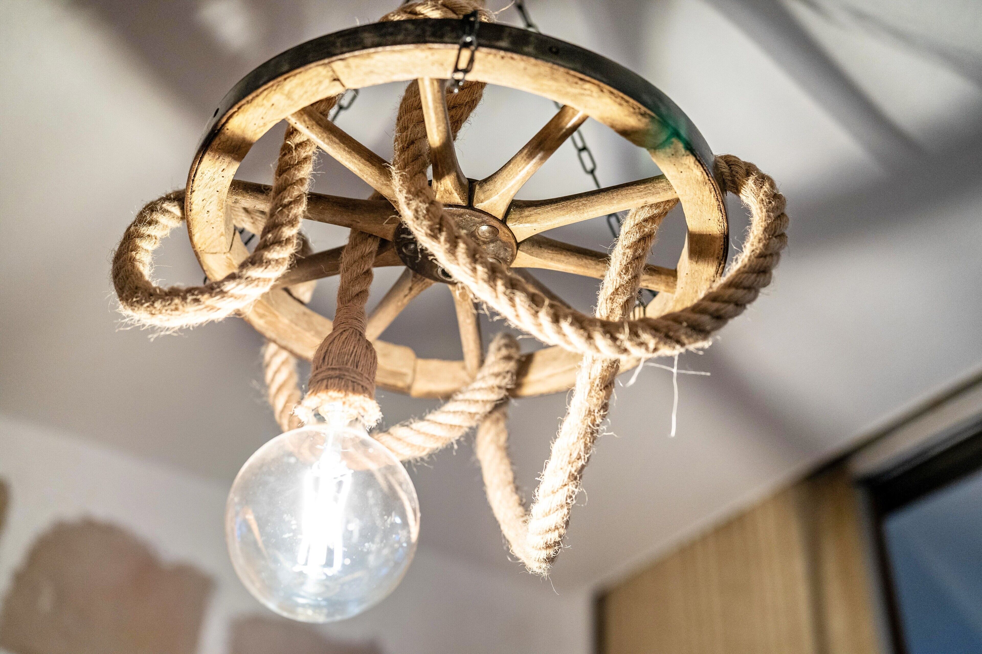 Een houten wiel kroonluchter met een gloeilamp eronder.